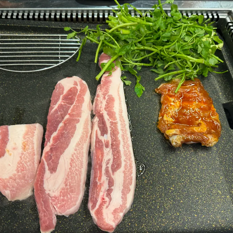 불판 위의 삼겹살과 미나리
