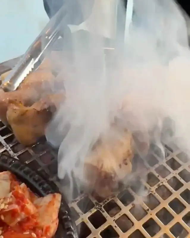 숯불 위에서 연기를 내며 구워지는 고기