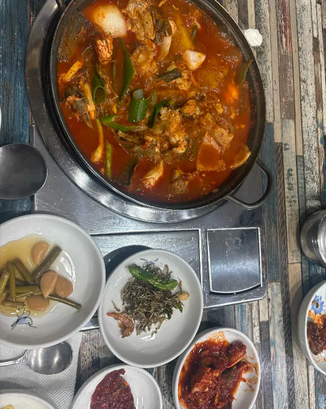 갈치조림 냄비와 함께 다양한 밑반찬이 테이블 위에 놓여 있다.