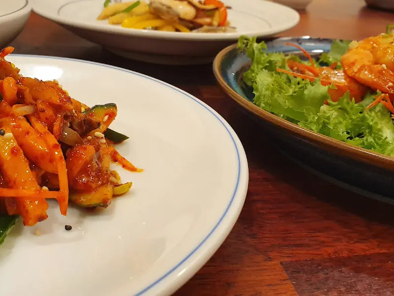 접시에 담긴 잡채, 샐러드, 떡갈비 등 다양한 한정식 요리들의 클로즈업 샷