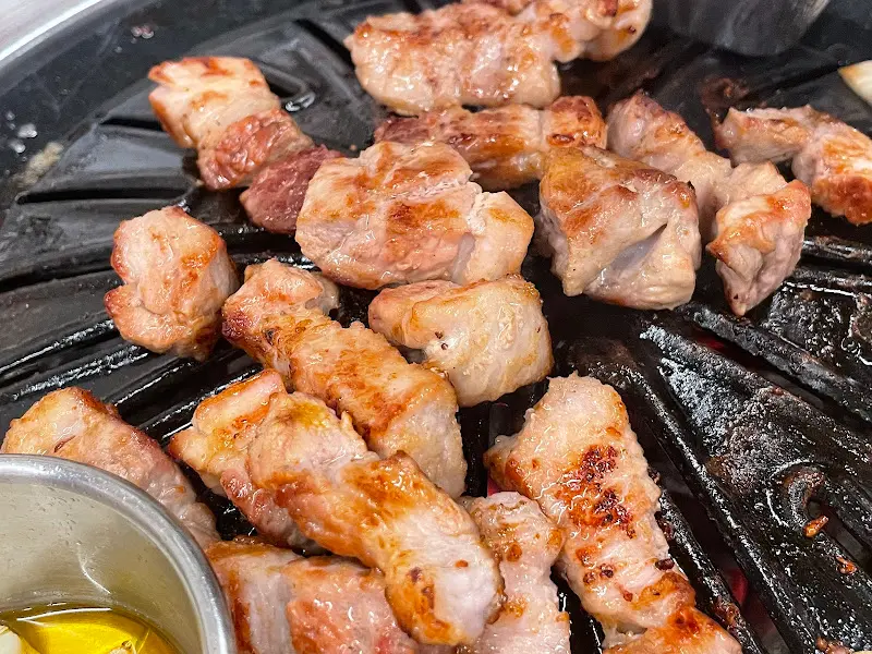 숯불 위에서 노릇하게 구워진 삼겹살이 먹음직스럽다.