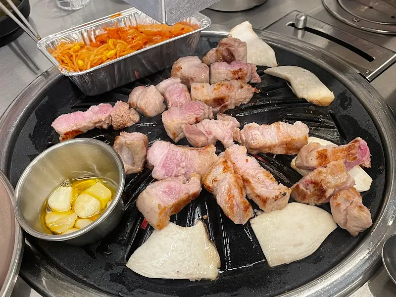 불판 위에 삼겹살, 갈매기살, 버섯을 가지런히 올려 굽는 모습