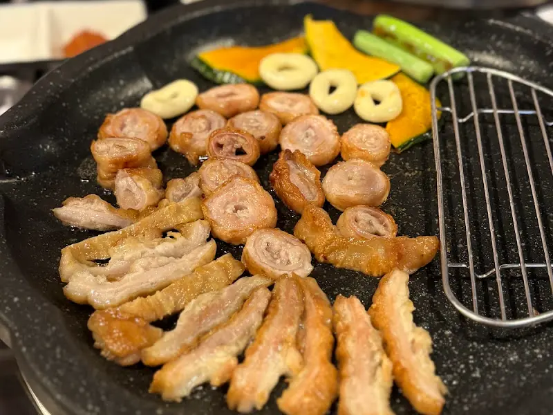 불판 위에서 구워지고 있는 막창과 곁들임 채소