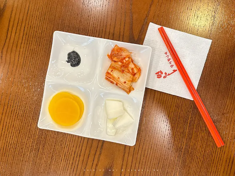 네 칸으로 나뉜 반찬 그릇에 담겨 나온 단무지, 양파, 춘장, 겉절이 김치의 모습