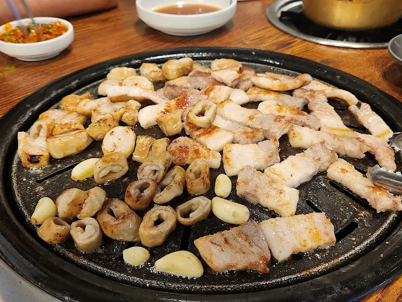 불판 위에서 구워지는 막창, 삼겹살, 마늘