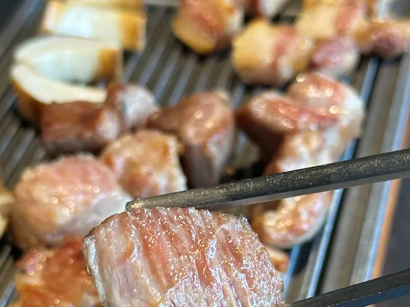 집게로 흑돼지 오겹살을 들어올리는 모습