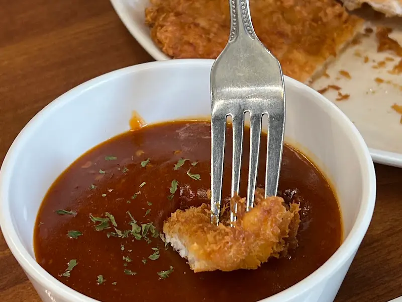 돈까스 한 조각을 소스에 찍어 올린 모습