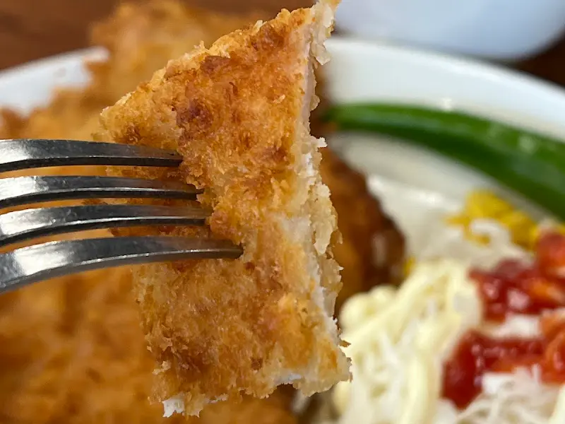 돈까스를 포크로 찍어 올린 클로즈업 사진