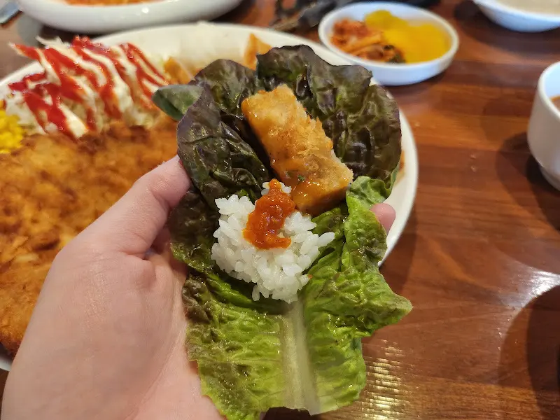 상추쌈에 돈까스를 싸서 먹는 모습