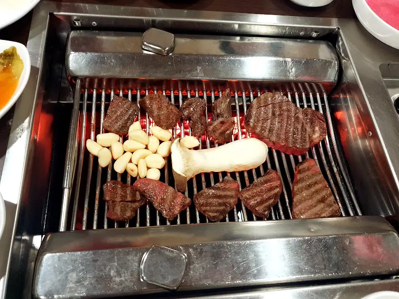 숯불 위에서 구워지는 등심과 마늘, 버섯