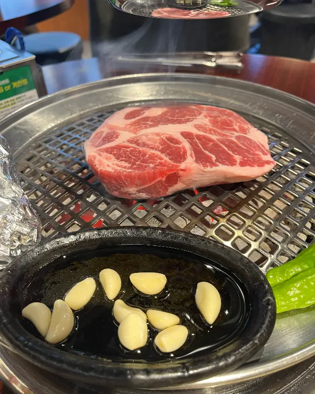 두툼한 동래목살이 숯불 위에 올려져 있다.