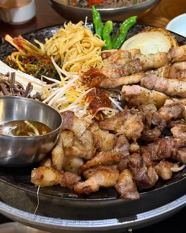 불판 위에 구워져 나온 꼬들살과 곁들임 채소의 모습