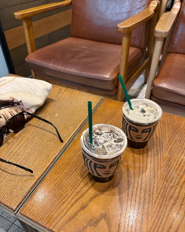 테이블 위에 놓인 스타벅스 컵 두 잔과 안경