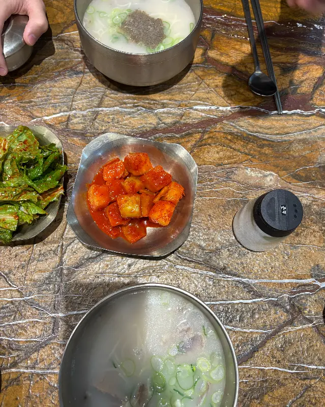 테이블 위에 놓인 설렁탕, 깍두기, 겉절이, 후추