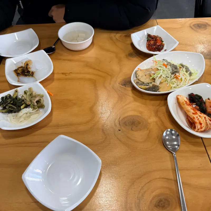 다양한 밑반찬들이 나무 테이블 위에 정갈하게 놓여 있는 모습