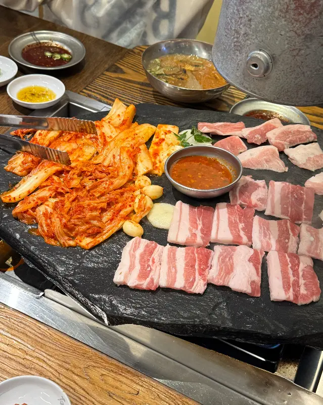 돌판 위에 김치와 삼겹살이 가지런히 놓여 있는 모습