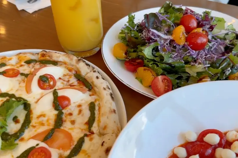 테이블 위에 놓인 마르게리따 피자, 샐러드, 오렌지 주스