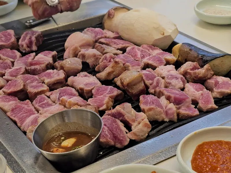 두툼한 목살과 버섯이 불판 위에 올려진 모습