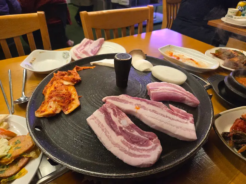 솥뚜껑 위에 구워지는 삼겹살과 김치