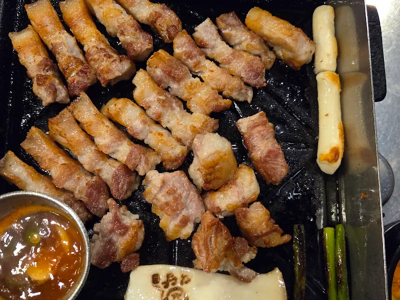 불판 가득 구워진 오겹살과 떡, 버섯의 모습