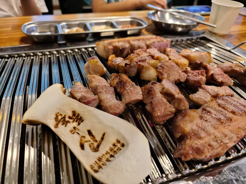 불판 위에서 익어가는 삼겹살과 버섯