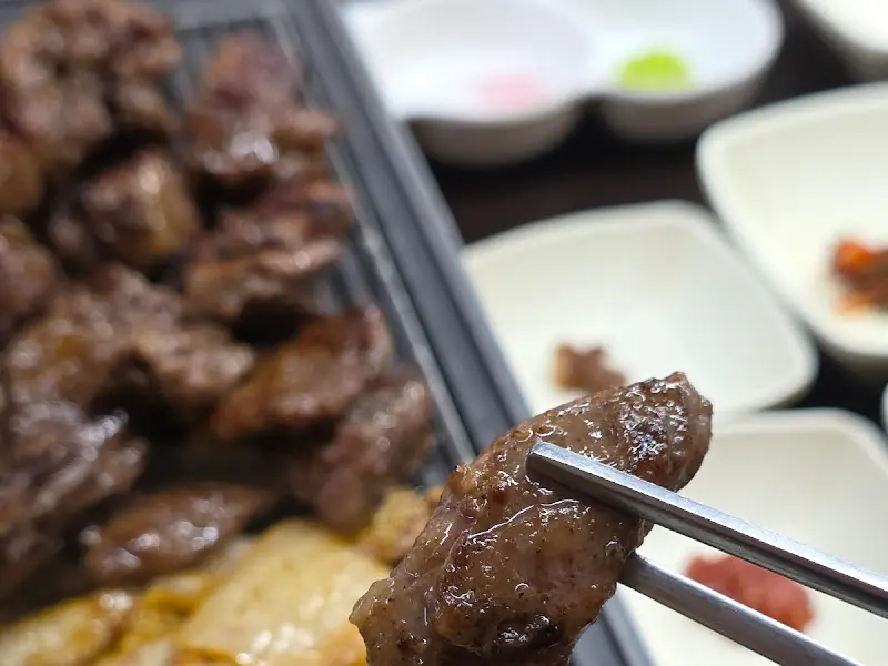 잘 구워진 고기 한 점을 젓가락으로 집어 올린 모습