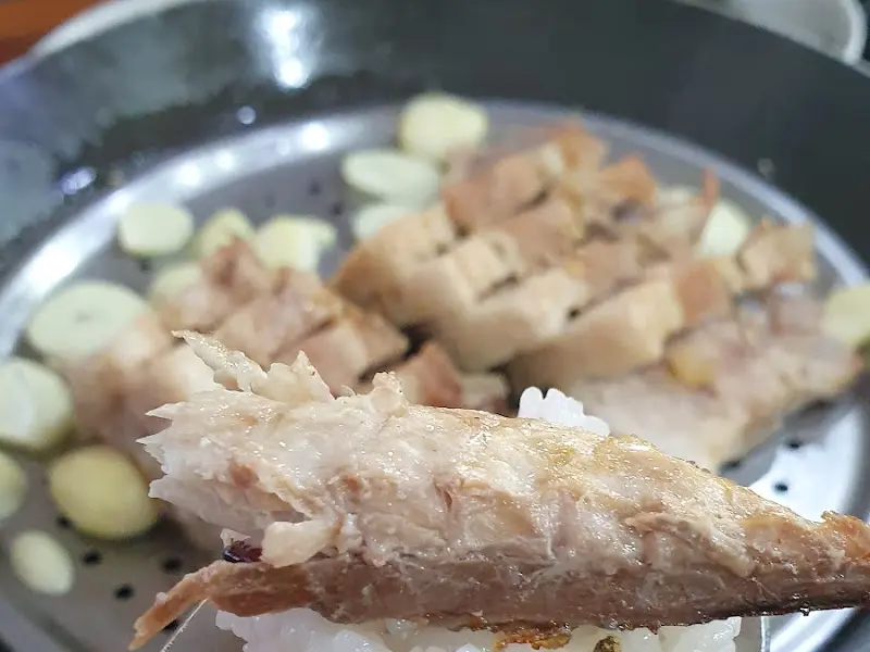 밥 위에 고등어 구이 살점을 올려 젓가락으로 집어 올린 모습