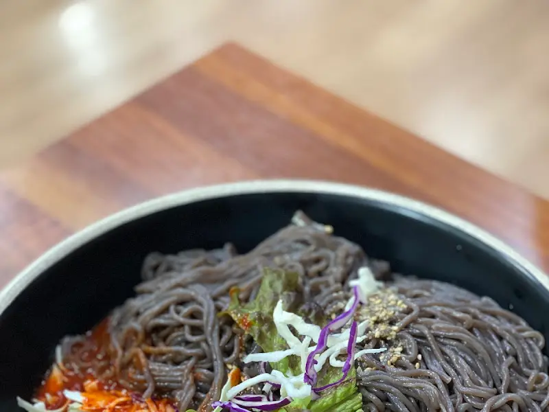 검은 면발의 막국수 위에 양념장이 올려져 있다.