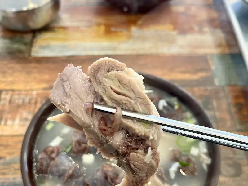 수저로 국밥 속 고기를 들어올리는 모습