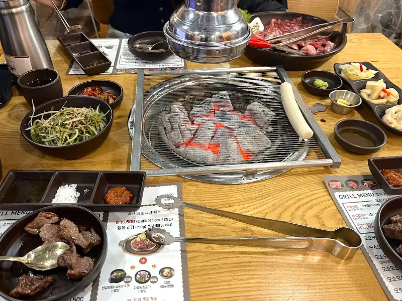 숯불 위에 올려진 고기와 다양한 반찬들