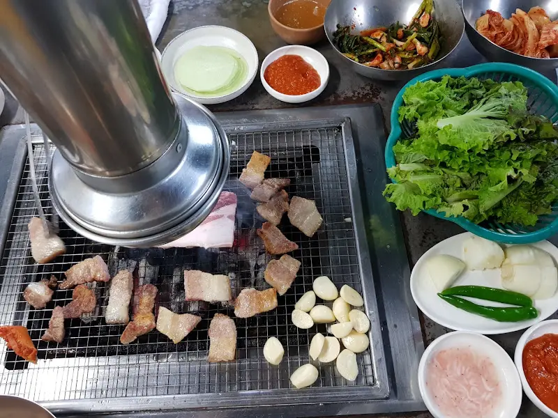 숯불 위에서 맛있게 익어가는 흑돼지 삼겹살과 гарлик