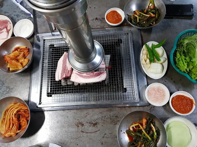 숯불 위에서 맛있게 익어가는 흑돼지 삼겹살과 김치