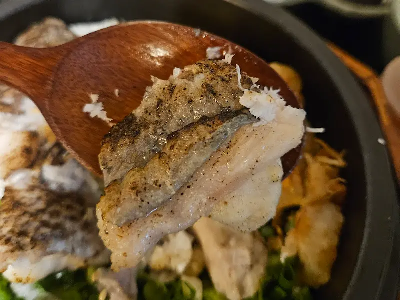 나무 주걱으로 갓 지은 도미솥밥을 푸는 모습