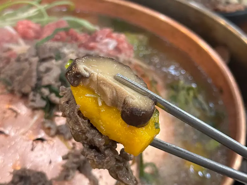 잘 익은 불고기 한 점을 젓가락으로 집어 올리는 모습