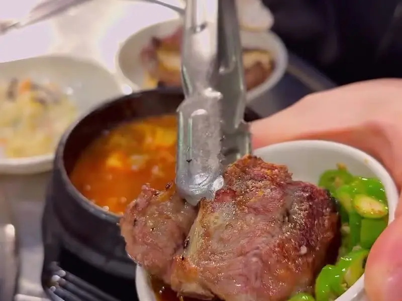 잘 구워진 생갈비를 집게로 들어 올리는 모습