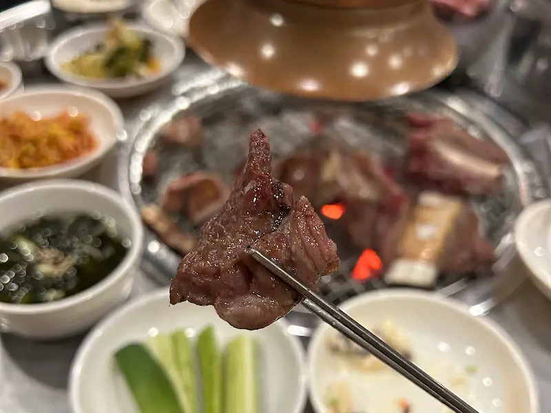 잘 익은 생갈비를 젓가락으로 집어 올리는 모습