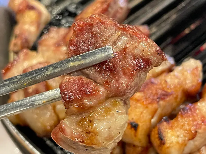 잘 구워진 고기를 젓가락으로 집어 올리는 모습