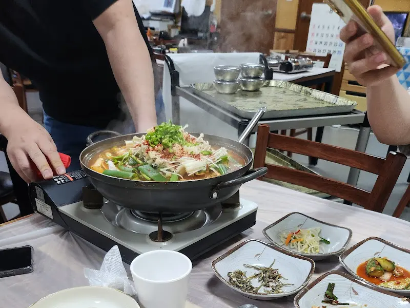 테이블 위 버너에 올려진 채 보글보글 끓고 있는 매운탕과 정갈하게 놓여진 밑반찬들