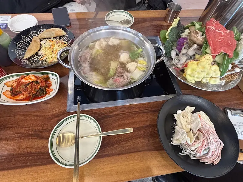 테이블 위에 놓인 샤브샤브, 만두, 김치