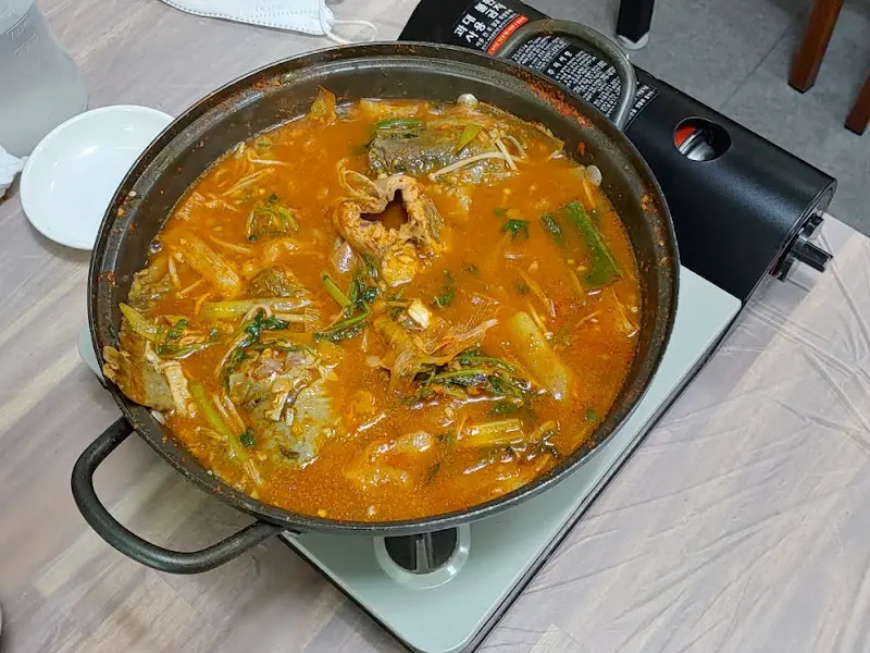 푸짐하게 끓여진 매운탕이 테이블 위 버너에서 뜨겁게 끓고 있다.