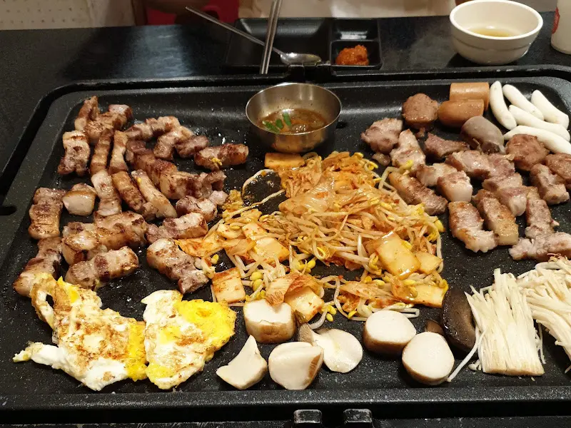 돌판 가득 올려진 초벌 삼겹살과 다채로운 곁들임