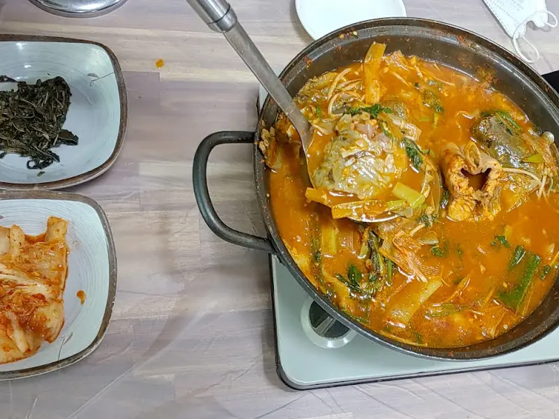 국자로 큼지막한 메기 머리를 들어올린 모습이 인상적이다.