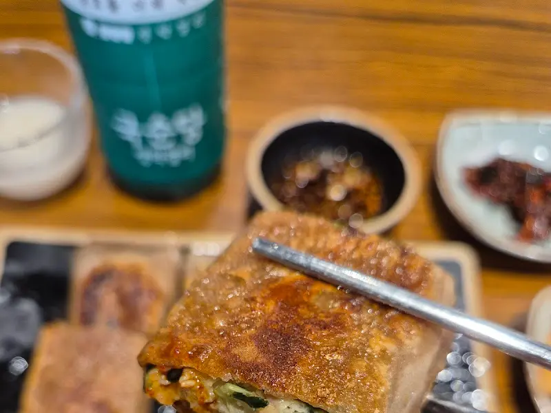 노릇하게 구워진 메밀전병을 젓가락으로 집어 올린 모습