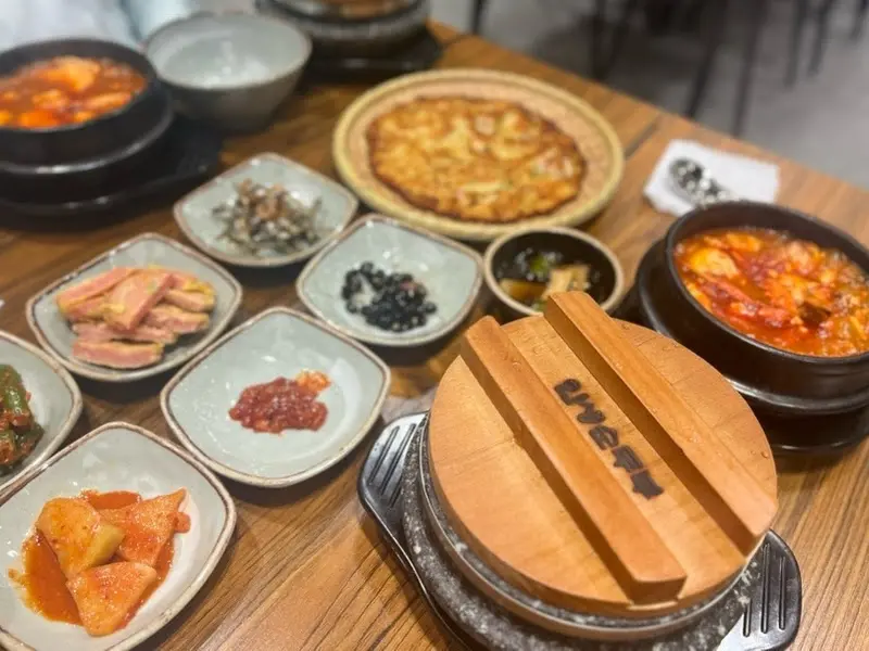 다채로운 밑반찬과 순두부찌개, 돌솥밥, 메밀전병이 한 상 가득 차려진 모습