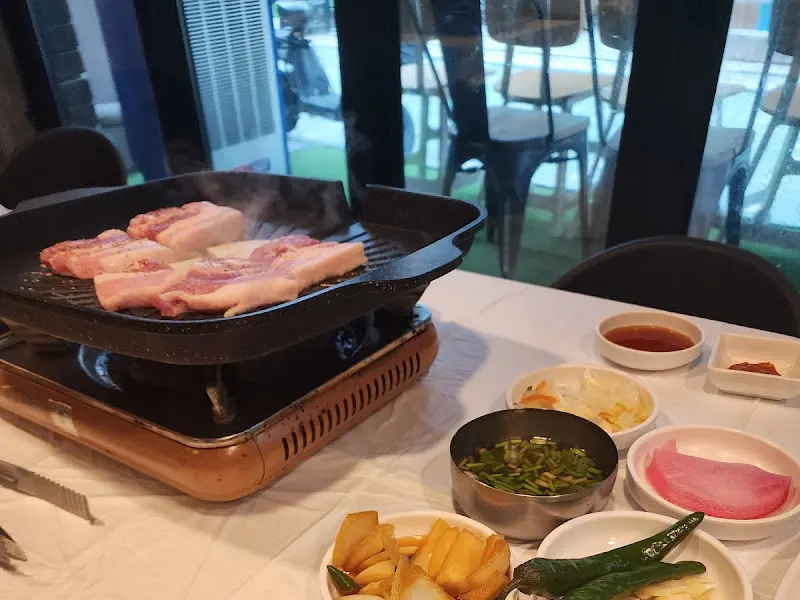 불판 위에서 익어가는 삼겹살과 미나리