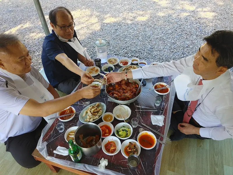 닭볶음탕을 가운데 두고 사람들이 옹기종기 모여 앉아 식사하는 모습