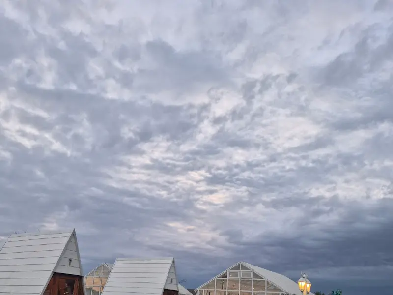저녁 무렵, 하늘을 가득 채운 구름과 A자형 오두막의 지붕선이 어우러진 풍경