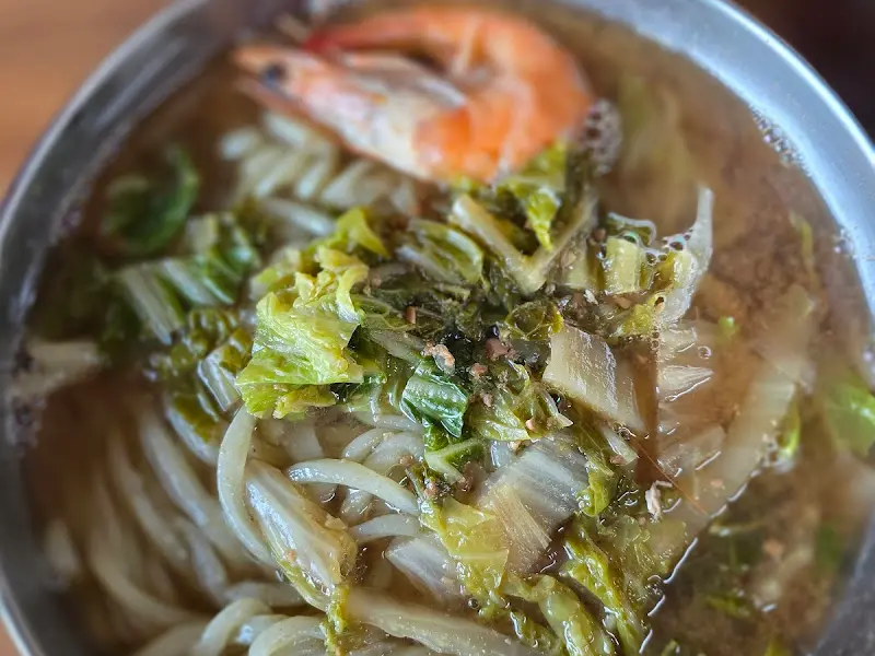 된장칼국수의 클로즈업 사진. 면발과 함께 새우, 배추 등의 재료가 보인다.