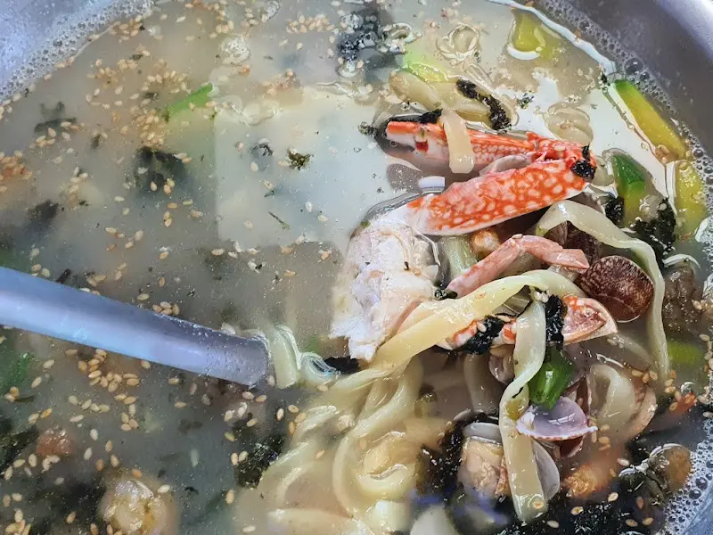 해물칼국수 국물에 숟가락 담근 모습