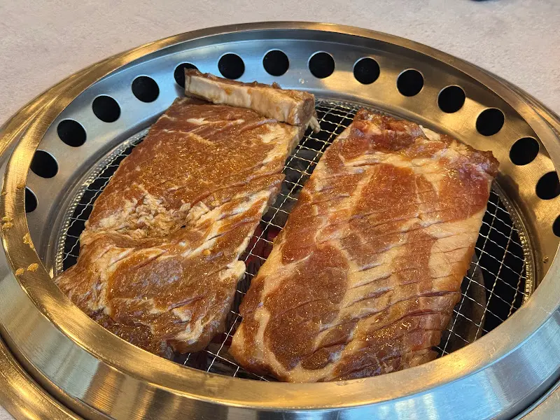 불판 위에서 맛있게 익어가는 두툼한 돼지갈비